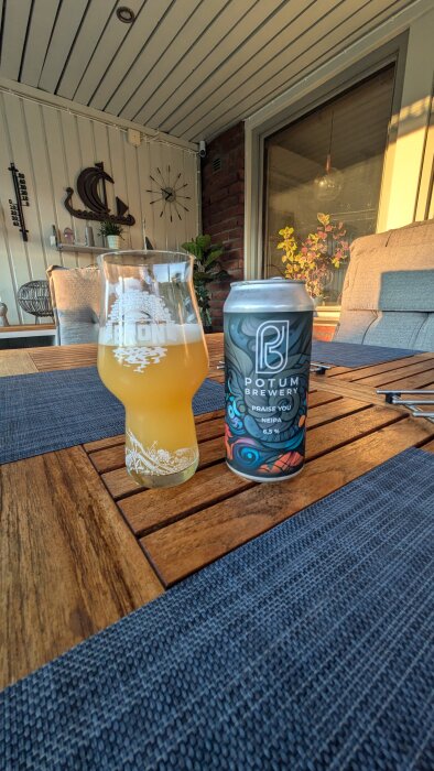 Ett glas öl från Bryggeri BRON och en burk med Potum Brewerys "Praise You" NEIPA på ett träbord i en uteplatsmiljö.