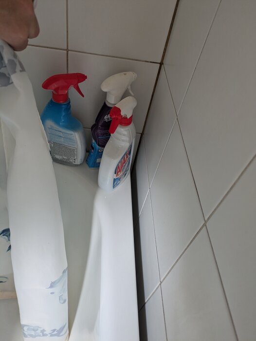 Glapp mellan badkar och vägg med några rengöringsmedel placerade på badkarskanten. Storleken på glappet är cirka 2,5-3 cm.