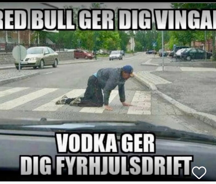 En person kryper på alla fyra över ett övergångsställe med en skämtsam text som jämför effekten av Red Bull och vodka.