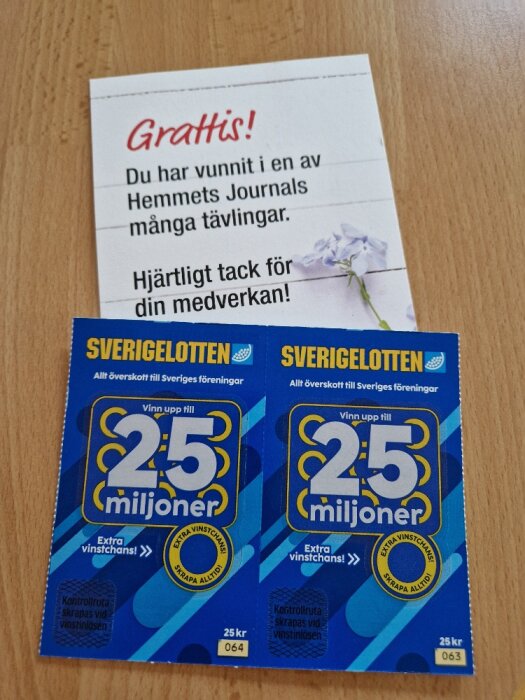 Två Sverigelotten-lotter som ligger på ett bord, tillsammans med ett grattiskort som informerar om en vinst från Hemmets Journals tävlingar.