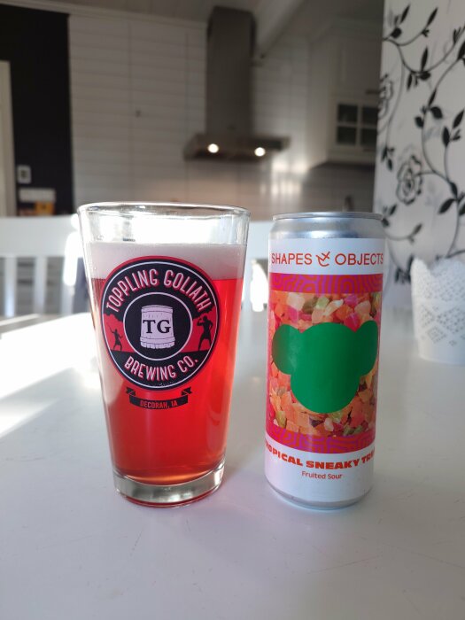 Ett glas med öl från Toppling Goliath Brewing Co. bredvid en burk Shapes & Objects Tropical Sneaky Treat Fruited Sour.