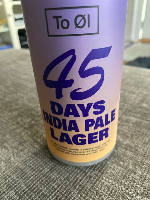 En burk med 45 Days India Pale Lager från To Øl står på ett bord. Text på burken beskriver ölets mognad och aromatiska smak.