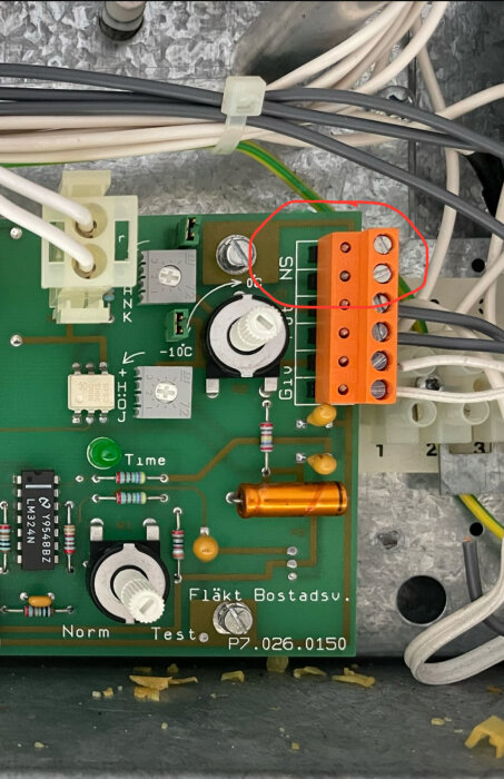 Närbild på ett styrkort för ett ventilationsaggregat med anslutningar och elektroniska komponenter, där "NS" anslutningarna har markerats med en röd cirkel.