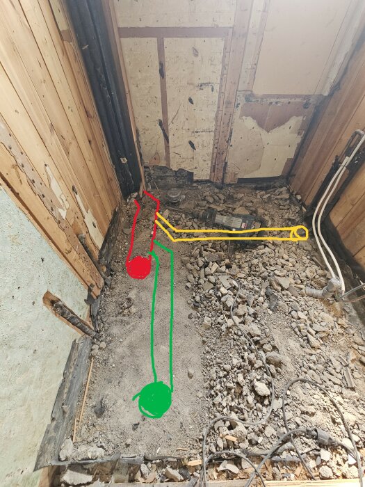 Utrymme under renovering med färgade markeringar för WC (röd), dusch (grön), och handfat (gul) på golvet, tillsammans med byggmaterial och verktyg.