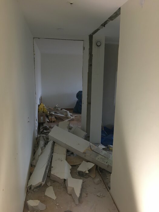 Nedriven gipsvägg i sovrum med trasiga gipsskivor på golvet mitt i en renovering.