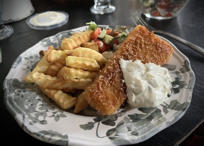 Tallrik med panerad fisk, pommes frites, sallad och färdigköpt citron- och dillsås.