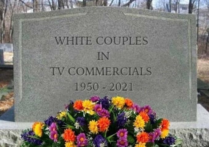 Gravsten med texten "WHITE COUPLES IN TV COMMERCIALS 1950-2021" ovanför en bukett färgglada blommor.