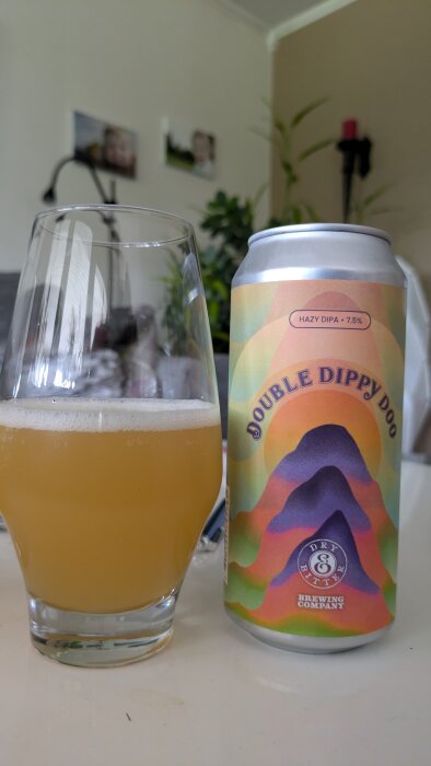 En burk med ölen "Double Dippy Doo" Hazy DIPA 7.5%, från Dry & Bitter Brewing Company, och ett glas med ljust gyllene öl på ett bord.