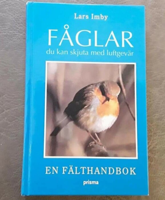 Boken "Fåglar du kan skjuta med luftgevär" av Lars Imby med bild på en rödhake på omslaget. En fälthandbok, prisma-förlag.