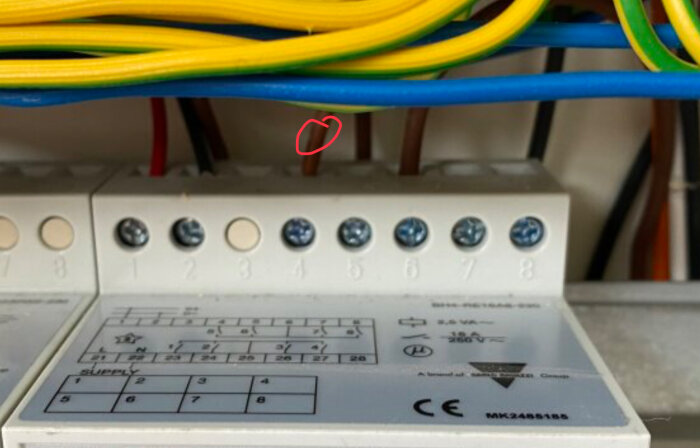 Elektriskt kopplingsschema med inverter, kablar och skruvterminaler. En kabel är markerad med en röd cirkel.