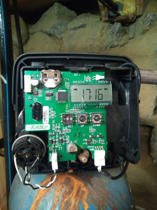 Kretskort i ett öppet elektroniskt filter med knappar och en digital skärm som visar tiden 17:16.