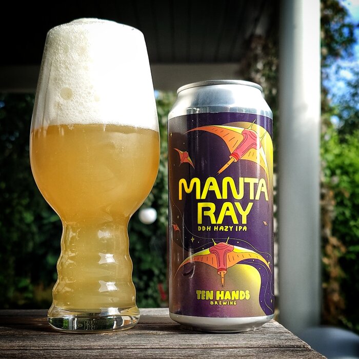 Ett glas fylld med skummande hazy IPA bredvid en ölburk Manta Ray från Ten Hands Brewing.