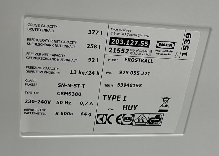 Närbild på typskylten på en Ikea Frostkall kyl-frys. Skylten visar tekniska specifikationer som nettovolym, effekt, spänning och kylmedel, modell 21552.