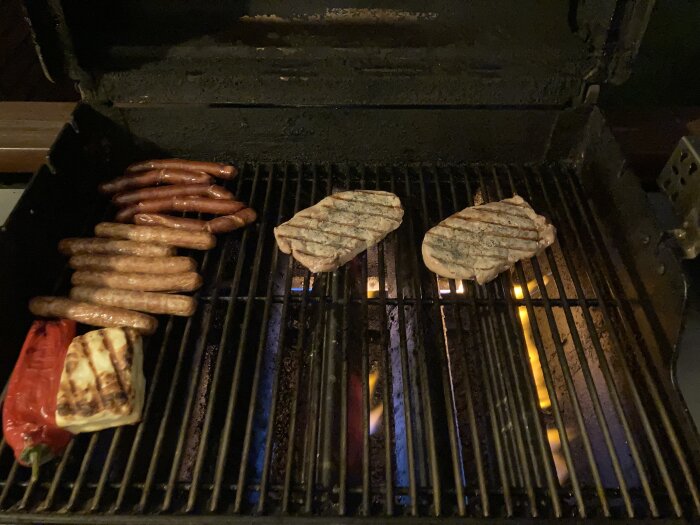 Kalventrecote, korv, paprika och ost grillas på en utomhusgrill.