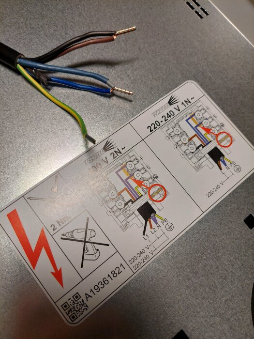 Schema för elkoppling på baksidan av en spishäll med exponerade kablar L1, L2, N och jord samt instruktioner för installation.