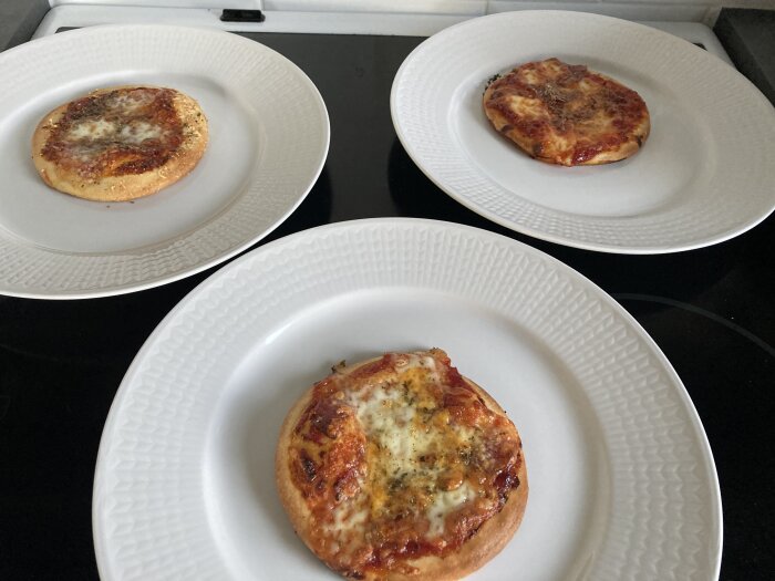 Tre bakeup-minipizzor med varierad topping på vita tallrikar.