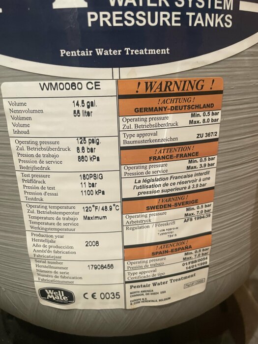 Etikett på hydropress med information om volym (58 liter), maximalt arbetstryck (8 bar), testtryck, arbetstemperatur, tillverkningsår (2008) och varningsmeddelanden på flera språk.