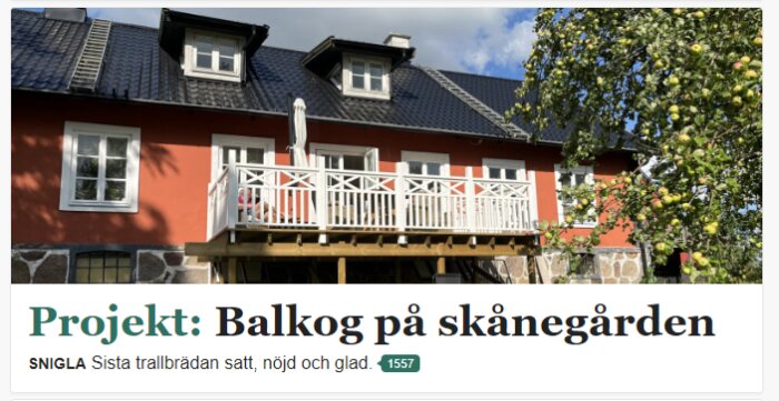 Ett rött hus med svart tak och en vit balkong, med en grönskande trädgård och ett äppelträd i förgrunden. Texten säger: Projekt: Balkog på skånegården.