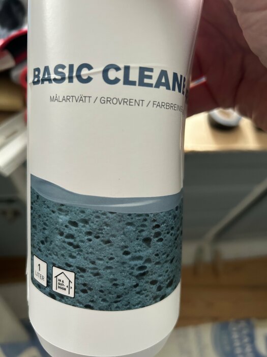 En närbild på en flaska med städmedlet "Basic Cleaner" med texten "målartvätt/grovrent/färgborttagning" samt etiketter för 1 liter och inomhus/utomhusbruk.