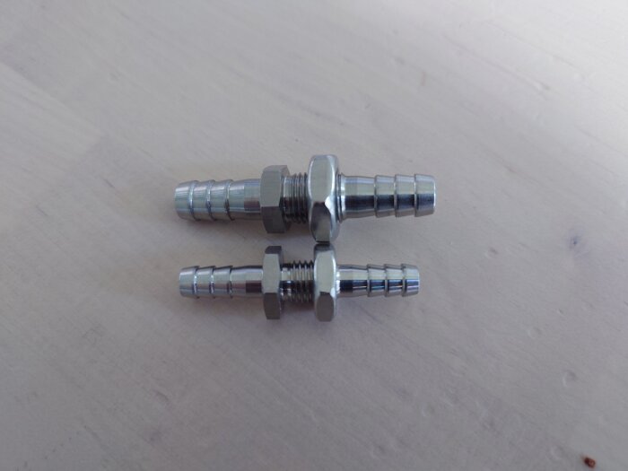 Två genomföringar i metall, en större och en mindre, som enligt produktbeskrivningen skulle ha en innerdiameter på 8 mm men har en ytterdiameter på 8 mm.