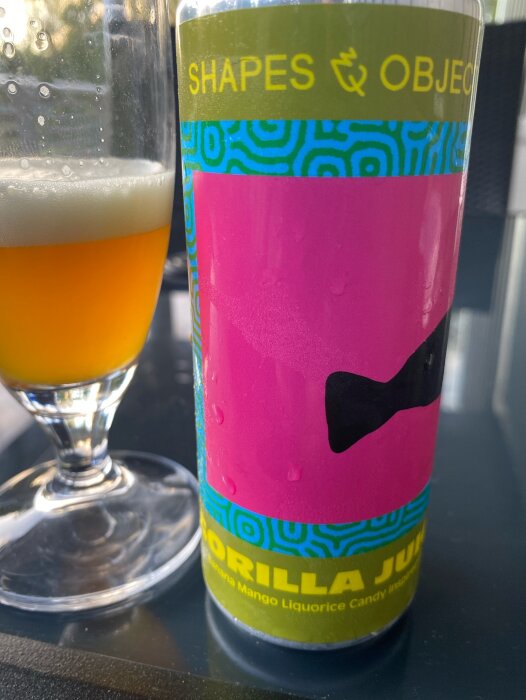 Ett glas öl bredvid en ölburk med etiketten "Shapes & Objects Gorilla Juju Banana Mango Liquorice Candy.