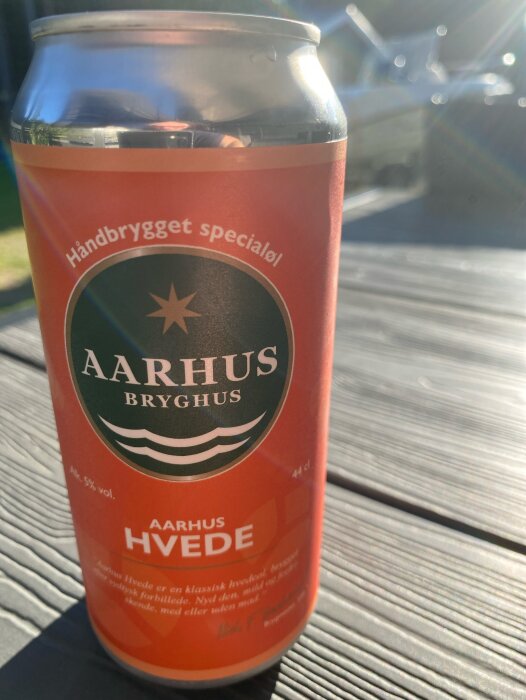 En burk Aarhus Hvede öl från Aarhus Bryghus står på ett bord utomhus i solljus.