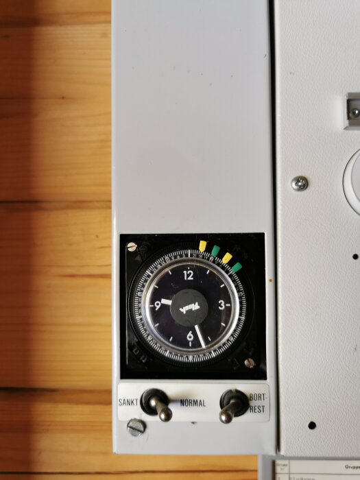 Timerenhet med urtavla och två brytare för inställning av elementdriftläge, med inställningsalternativen "Sänkt", "Normal" och "Bortrest".