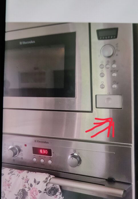 Mikrovågsugn från Electrolux med röd markering som pekar på startknapp, vilken enligt användare ibland fastnar vid stängning av dörren.