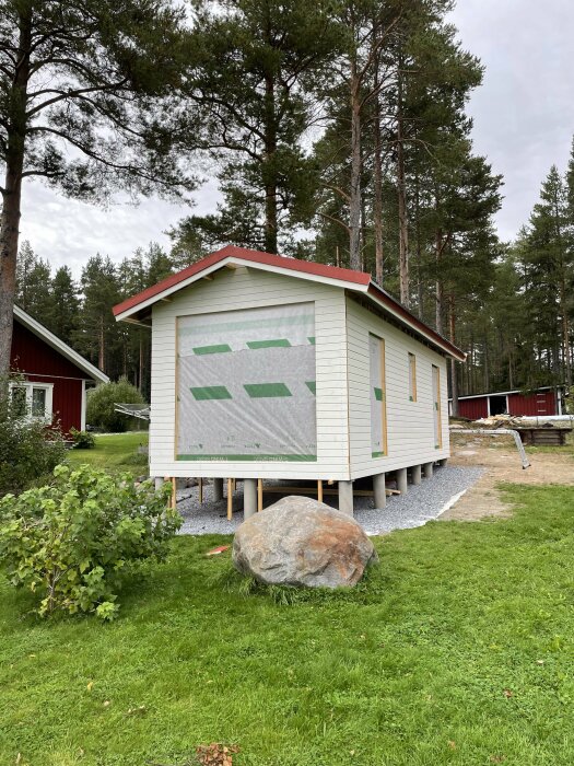 En nästan färdig byggnad med vit panel och plåttak. Byggnaden saknar dörrar och fönster, och nockplåt samt gavelbeslag är inte på plats än.