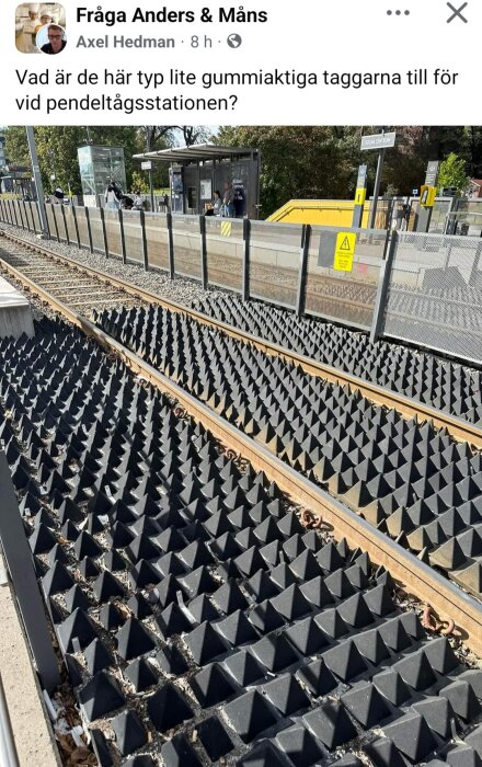 Gummiliknande taggar längs järnvägsspår vid en pendeltågsstation, med en fråga om deras syfte.