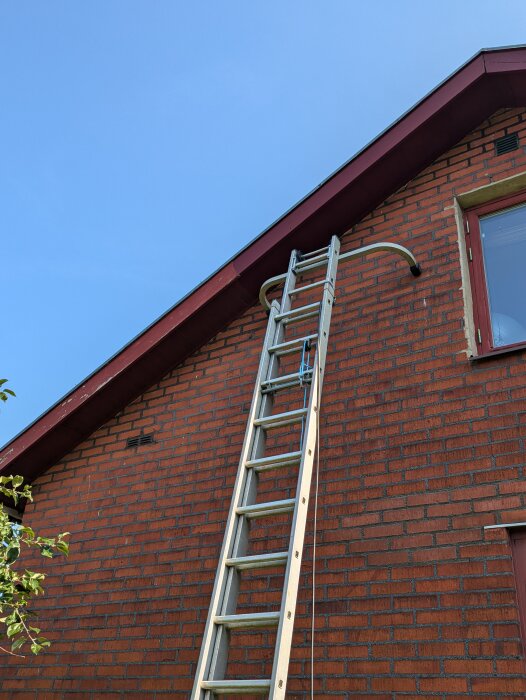 Stege lutad mot tegelhus under pågående målning av vindskiva.