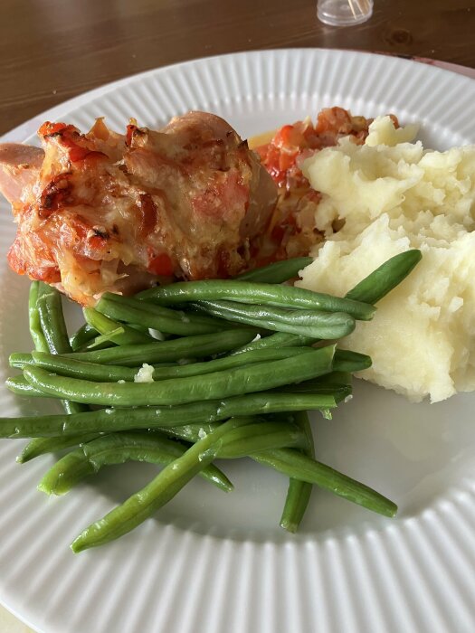 Tallrik med ugnsfalu fylld med lök, vitlök och paprika, toppad med Västerbottenost. Serveras med haricot vert och potatismos.