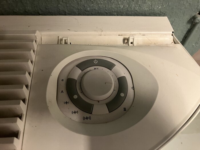 Närbild på en inställningspanel för ett värmeelement med flera symboler, inklusive en strömknapp och temperaturinställningar.