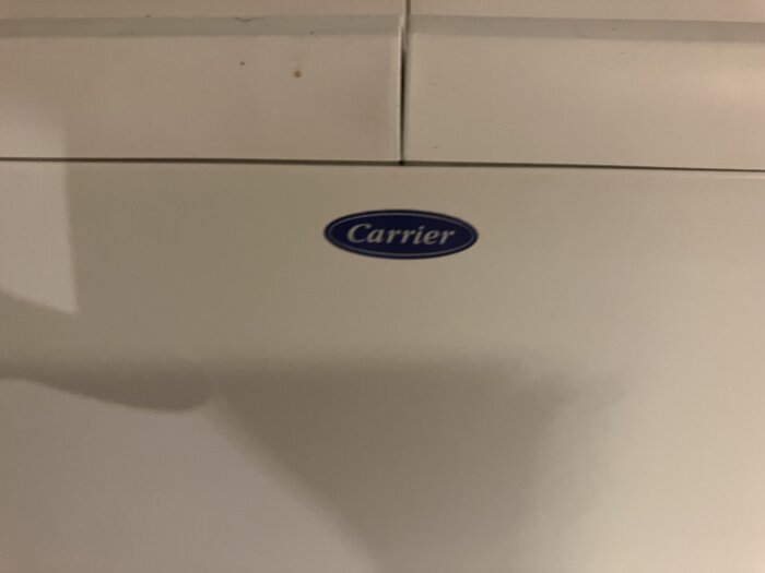 Vit värmepump i tvättstugan med "Carrier"-logotypen synlig, användare frågar om orsaken till att varmluften inte fungerar.