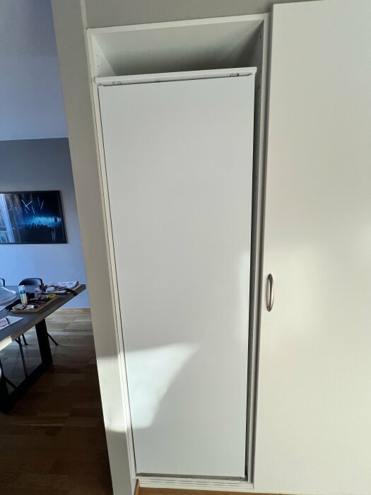 Integrerat kylskåp från Electrolux med vit dörrpanel i ett kök. Kylskåpet saknar hål på framsidan för gångjärn och dörrpanelen väger 18 kg.