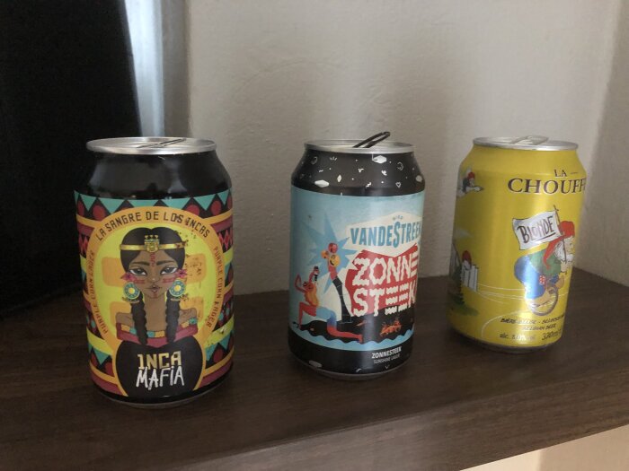 Tre ölburkar stående på en hylla: Inca Mafia, Vandestreek Zonnesteek och La Chouffe Blonde.