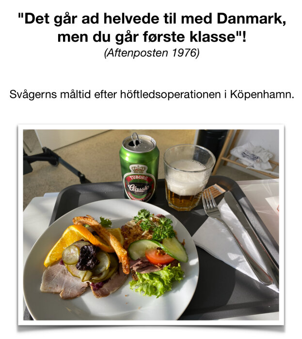 Tallrik med måltid innehållande bröd, sallad, tomat, gurka, kött och apelsinskivor samt en öppnad Tuborg Classic ölburk och glas med öl på en bricka.