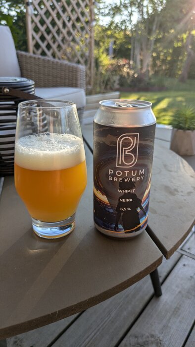 Burk och glas med Potum Brewerys Whip It NEIPA på ett bord i trädgårdsmiljö, drycken har en alkoholhalt på 6,5%.