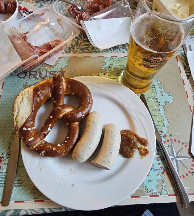 Bretzel, Weißwurst med senap och ett glas öl på ett bord, Oktoberfest-mat ovanpå en karta över Orust.