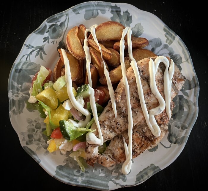 Tallrik med grillad kyckling, klyftpotatis, grönsallad och bearnaisesås.