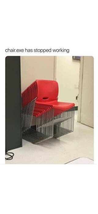 Staplade röda plaststolar med metallben står lutade mot en vägg, med texten "chair.exe has stopped working" ovanför.