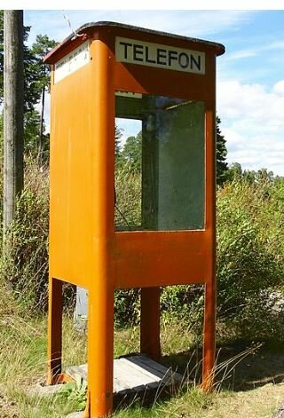 Orange telefonkiosk utomhus med ordet "Telefon" skrivet ovanpå.