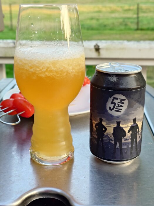 En halvt fryst öl i ett glas bredvid en öppnad, kall ölburk märkt "5 Man" på ett bord utomhus.