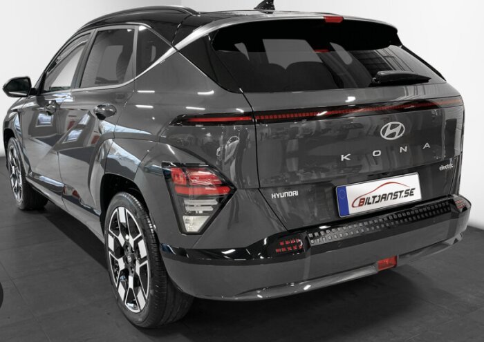 Bakre vyn av en mörk Hyundai Kona Electric parkerad inomhus.