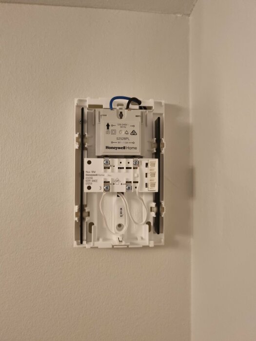 Installerad väggmonterad termostat från Honeywell Home med synliga kablar och komponenter.