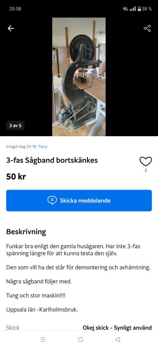 Stor 3-fas sågklinga bortskänkes, står på bord i ett rum. Synliga remskivor och motor vid botten av maskinen.