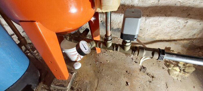 Gammal Zilmet-hydropressinstallation med manometer och tryckströmbrytare, liten spann placerad under för att fånga upp läckage samt Aqara-vattendetektor på golvet.