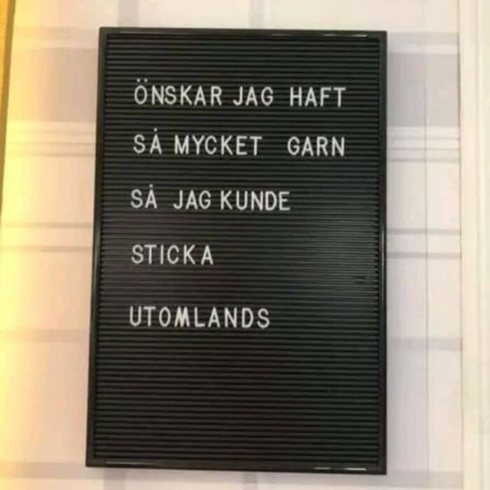 Skylt med texten "Önskar jag haft så mycket garn så jag kunde sticka utomlands" i vita bokstäver på svart bakgrund.