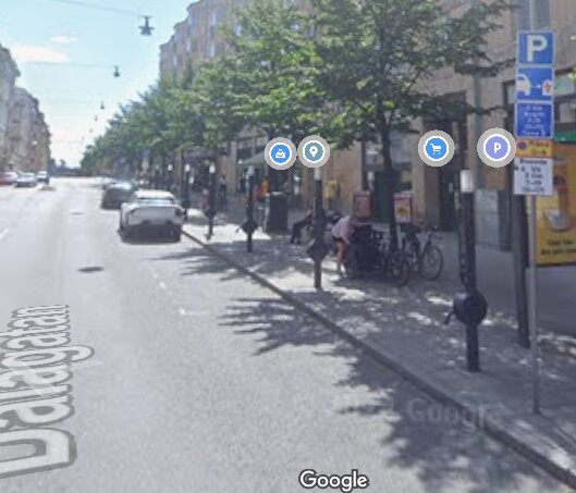 Gata med parkerade bilar och cyklar, träd längs trottoaren och skyltar som visar parkeringsplatser i Stockholm.