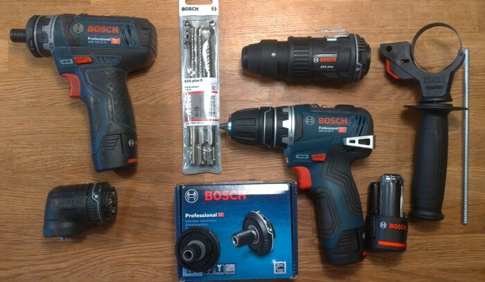 Bosch skruvdragare och borrmaskiner med tillbehör på ett träbord. Synliga produkter inkluderar GSR12V-15FC och GSR12V-35FC, borrtillsatser och batteri.